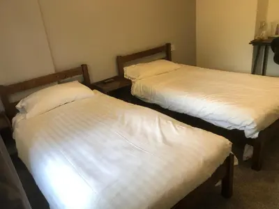 two beds in a room with white sheets at Abbeyfield Guesthouse in Cambridge