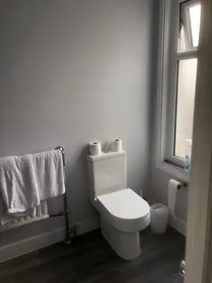 a bathroom with a toilet and a window and towels at Abbeyfield Guesthouse in Cambridge