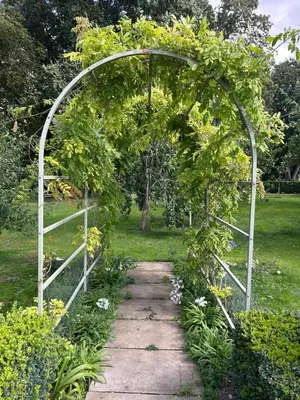 an arbor with a pathway through a garden at Meesden Hall in Meesden