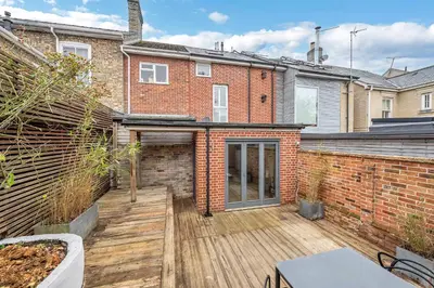 an empty backyard with a wooden deck in front of a brick building at 7D Albert St - sleeps 4 guests with parking on request in Bury Saint Edmunds