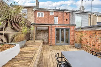 a patio with a table and chairs in front of a brick building at 7D Albert St - sleeps 4 guests with parking on request in Bury Saint Edmunds