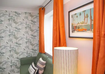 a living room with orange curtains and a green couch at 3x Bed Elegant House with Private Parking in Sawston