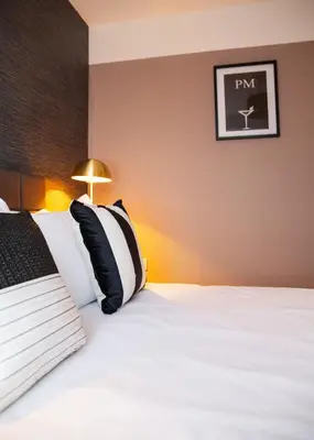 a hotel room with a bed with black and white pillows at 3x Bed Elegant House with Private Parking in Sawston