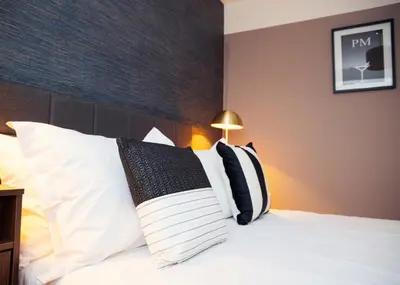 a hotel room with a bed with white pillows at 3x Bed Elegant House with Private Parking in Sawston