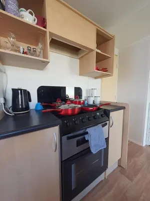 a kitchen with a stove with pots and pans on it at Buxton's Holiday Home - Park Holiday's complex - Beach Access - Free WiFi in Saint Osyth
