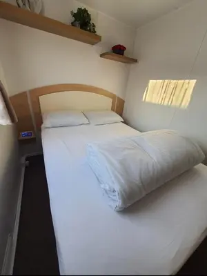 a small bedroom with a bed with white sheets at Buxton's Holiday Home - Park Holiday's complex - Beach Access - Free WiFi in Saint Osyth