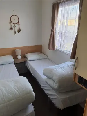 two twin beds in a room with a window at Buxton's Holiday Home - Park Holiday's complex - Beach Access - Free WiFi in Saint Osyth