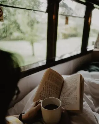 a person reading a book and a cup of coffee at Mind The Gap in Preston