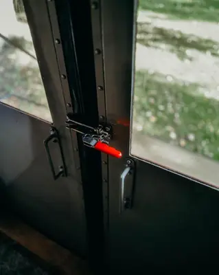 a door with a red handle on a train at Mind The Gap in Preston
