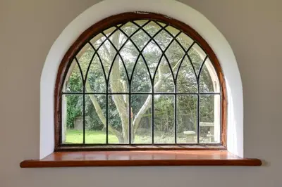 an arched window with a view of a tree at Acorn Cottage at Finchingfield Holiday Cottages in Finchingfield