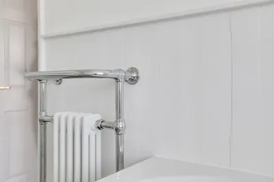a bathroom with a radiator and a towel rack at Acorn Cottage at Finchingfield Holiday Cottages in Finchingfield