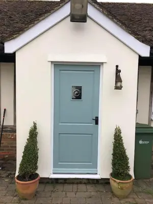 a blue door on a white house with two potted plants at Acorn Cottage at Finchingfield Holiday Cottages in Finchingfield