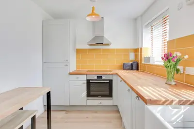 a kitchen with white cabinets and yellow tiles at Acorn Cottage at Finchingfield Holiday Cottages in Finchingfield