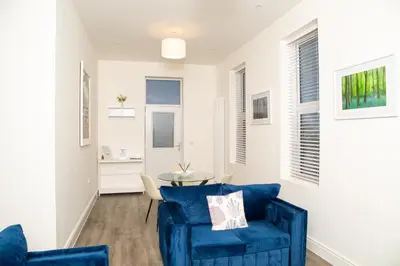 a living room with a blue couch and a table at Seaview Apartments - 28-29 Marine Parade, Harwich - Perfect for business & long term stays in Dovercourt