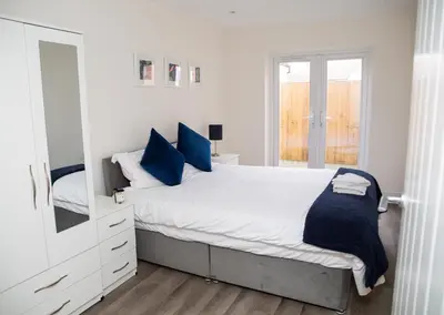 a bedroom with a bed with blue pillows and a mirror at Seaview Apartments - 28-29 Marine Parade, Harwich - Perfect for business & long term stays in Dovercourt