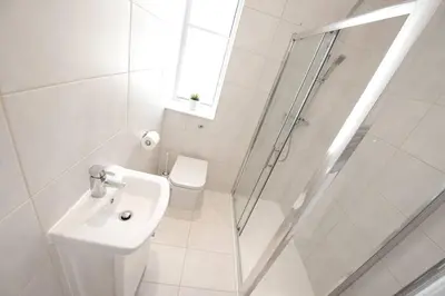 a white bathroom with a sink and a shower at Seaview Apartments - 28-29 Marine Parade, Harwich - Perfect for business & long term stays in Dovercourt