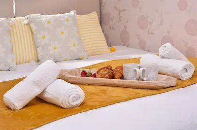 a tray with towels and a cat on a bed at Highwoods Haven Luxury Stay with Garden and Parking in Mile End