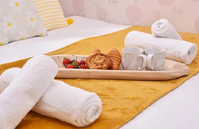 a tray of food on a bed with towels at Highwoods Haven Luxury Stay with Garden and Parking in Mile End