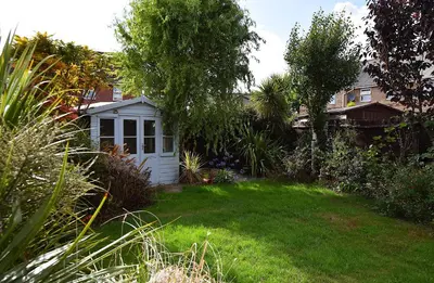 a small white shed in the middle of a yard at Highwoods Haven Luxury Stay with Garden and Parking in Mile End