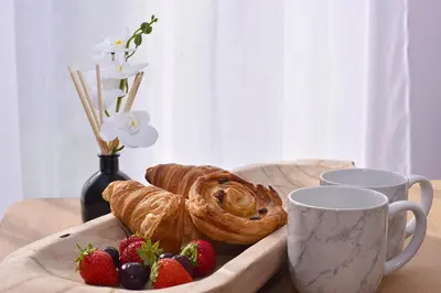 a wooden table with a tray of pastries and strawberries at Highwoods Haven Luxury Stay with Garden and Parking in Mile End
