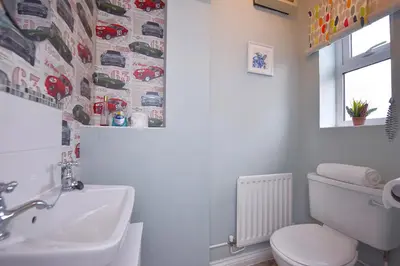a bathroom with a white toilet and a sink at Highwoods Haven Luxury Stay with Garden and Parking in Mile End