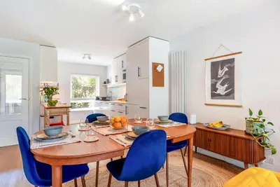a dining room with a wooden table and blue chairs at Brunswick Terrace in Cambridge