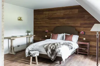 a bedroom with a bed with a wooden wall at Royal Racing Retreat in Newmarket in Newmarket
