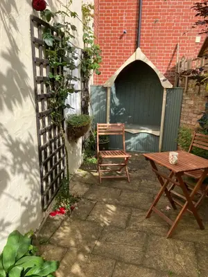 a patio with a table and a bench and a fence at Driftwood Cottage in Harwich