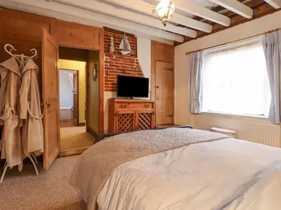 a bedroom with a large bed and a television at Driftwood Cottage in Harwich