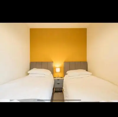 two beds in a room with a yellow wall at Chique & Modern Style Apartment in Cambridge