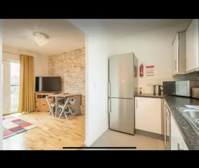 a kitchen with a stainless steel refrigerator and a table at Chique & Modern Style Apartment in Cambridge