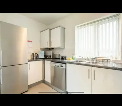 a kitchen with white cabinets and a stainless steel refrigerator at Chique & Modern Style Apartment in Cambridge
