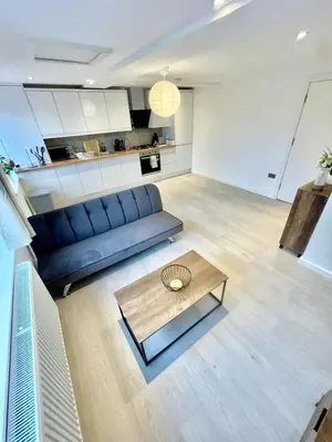 a living room with a blue couch and a coffee table at Modern 2 bedroom apartment in cambridge in Milton