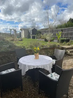 a table and chairs with a white table and flowers on it at Chestnut Cottage in Great Ellingham