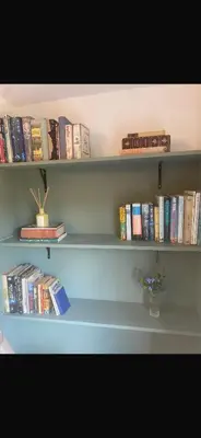 a book shelf filled with books and a vase of flowers at Chestnut Cottage in Great Ellingham