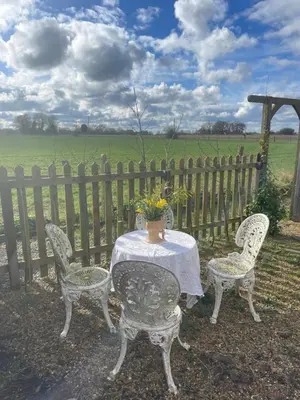 a table with two chairs and a vase on it at Chestnut Cottage in Great Ellingham