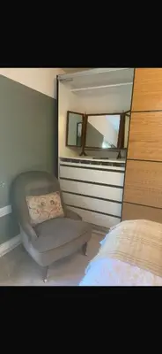 a bedroom with a chair and a mirror at Chestnut Cottage in Great Ellingham