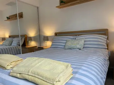 a bedroom with a blue and white bed with mirrors at Central Leigh, on the Broadway, private gated parking, balcony in Southend-on-Sea