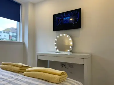 a room with a bed with a table with a mirror at Central Leigh, on the Broadway, private gated parking, balcony in Southend-on-Sea