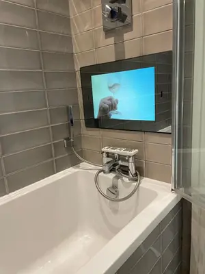 a bathroom with a sink with a tv on the wall at Central Leigh, on the Broadway, private gated parking, balcony in Southend-on-Sea