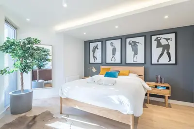 a bedroom with a large bed with four pictures on the wall at Fabulous Central Apt With Balcony & Parking in Cambridge