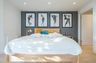 a bedroom with a large white bed with four pictures on the wall at Fabulous Central Apt With Balcony & Parking in Cambridge
