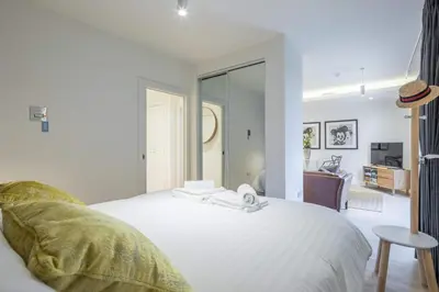 a bedroom with a white bed and a living room at Stunning Central Apt With Parking in Cambridge
