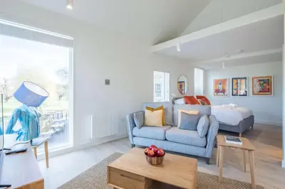 a living room with a blue couch and a bed at Luxury Central Apt Riverside Views & Parking in Cambridge