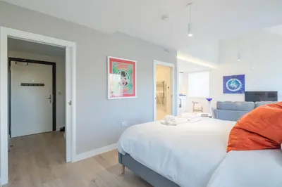 a white bedroom with a bed and a couch at Luxury Central Apt Riverside Views & Parking in Cambridge