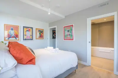 a bedroom with a white bed and paintings on the wall at Luxury Central Apt Riverside Views & Parking in Cambridge
