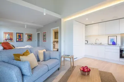 a living room with a blue couch and a kitchen at Luxury Central Apt Riverside Views & Parking in Cambridge