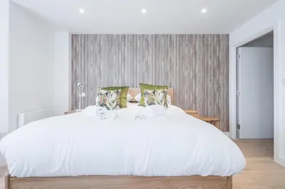 a white bedroom with a large white bed with pillows at Stunning Central Apt - Balcony & Parking in Cambridge