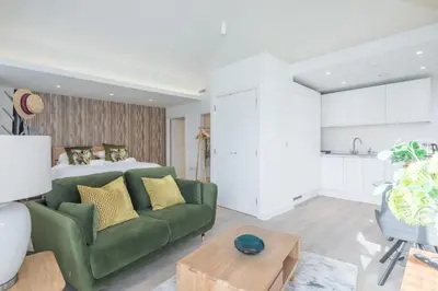 a living room with a green couch and a bed at Stunning Central Apt - Balcony & Parking in Cambridge