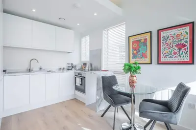 a white kitchen with a glass table and chairs at Stunning Central Apt - Balcony & Parking in Cambridge